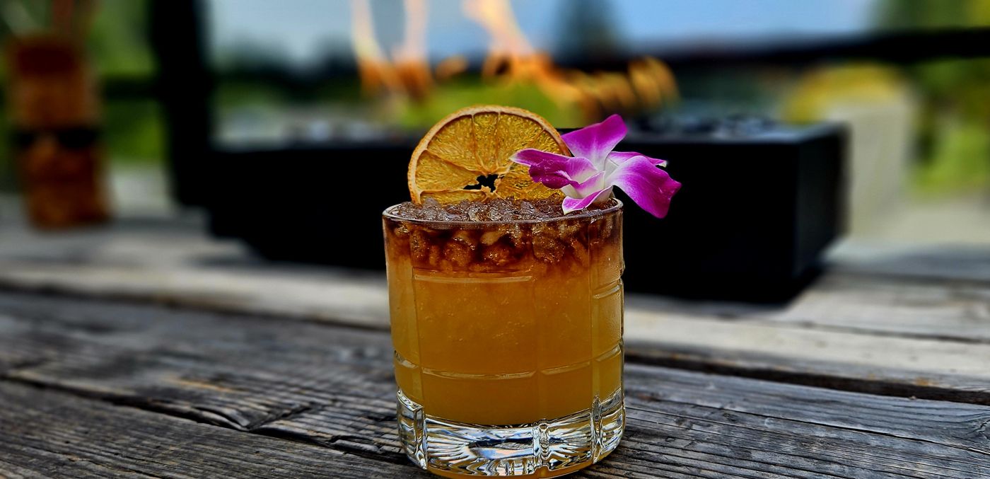 Tiki cocktail with a dehydrated orange wheel and orchid